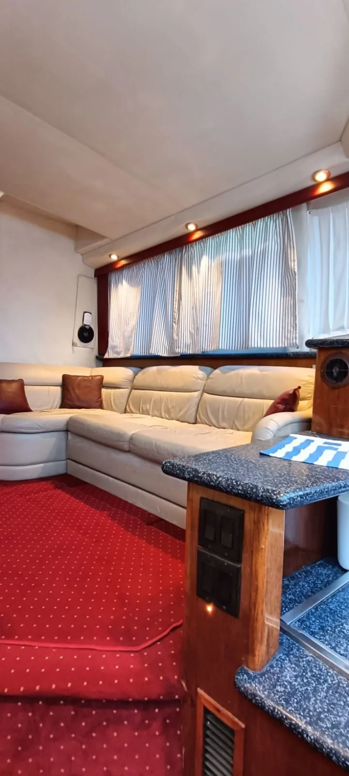 The salon lounge, a long cream leather sofa beneath striped curtains